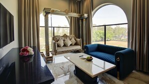 Ein geräumiges Wohnzimmer mit großem Fenster, einem blauen Sofa, einem weißen Couchtisch und einem dekorativen Bogen.