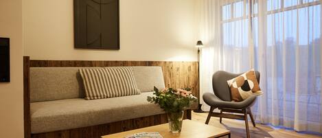 Una sala de estar moderna con sofá, sillón, mesa de centro y un jarrón de flores.