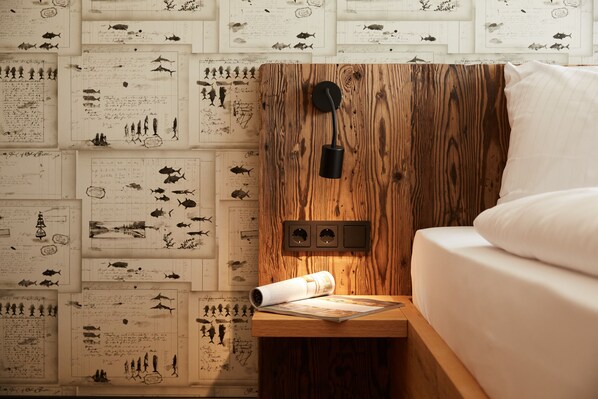 A bedroom with a wooden headboard, a bed with white bedding, and a nightstand with a rolled-up map. - Binnendiek Resort Büsum Haus 2 Comfort - Apartment 3 (Büsum)
