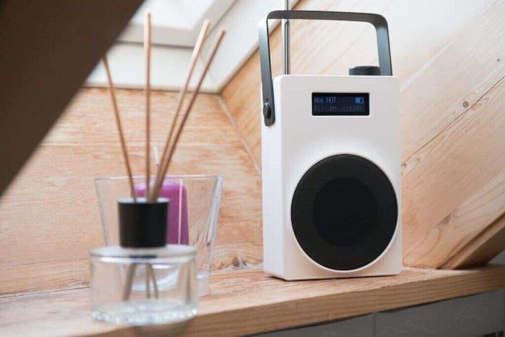 Un altavoz portátil con pantalla digital sobre una superficie de madera.
