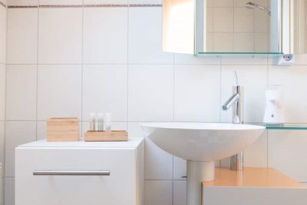 A modern bathroom with a white sink, a mirror, and a glass shower enclosure.