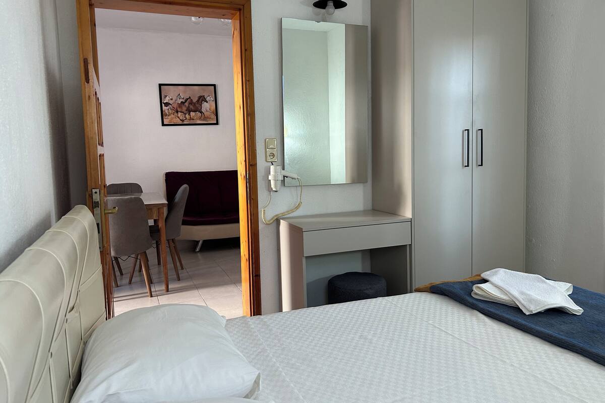 A bedroom with a bed, a desk, a chair, a wardrobe, and a mirror.