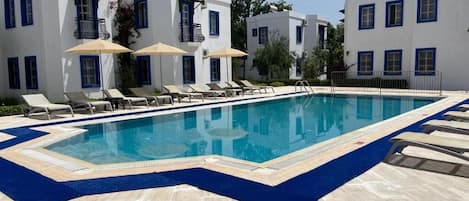 Una piscina al aire libre de temporada, sombrillas