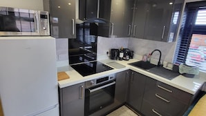 A compact kitchen with a microwave, stove, oven, and sink.