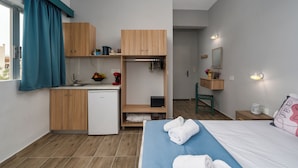 Et moderne hotelværelse med tekøkken, seng med håndklæder, et natbord og et spejl.