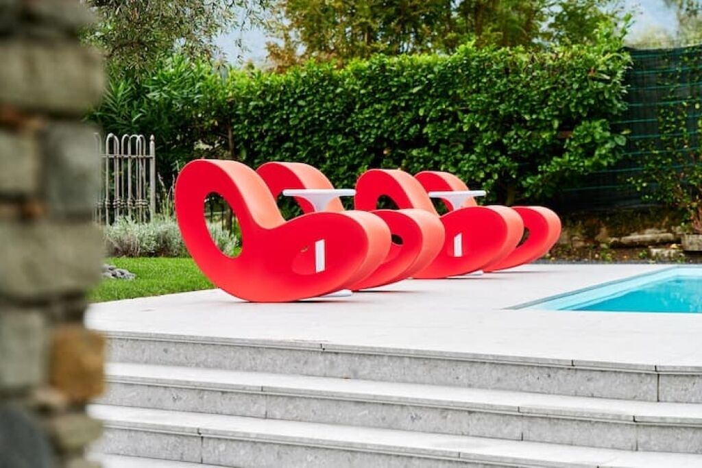 Sillas rojas al aire libre en fila junto a una piscina.