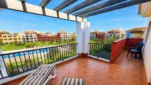 Un balcón con vista a una piscina y edificios residenciales.