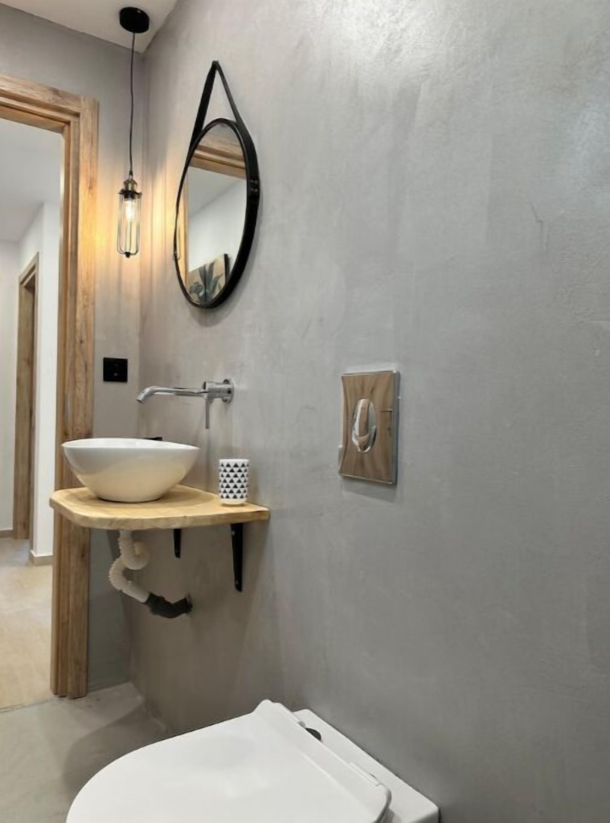 A bathroom with a white sink, a mirror, and a light fixture.