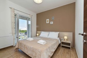 A bedroom with a bed, bedside tables, a window with curtains, and a view of the outside. - Holiday apartment with air conditioning and outdoor pool (Fažana)