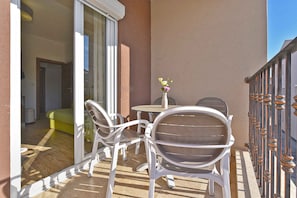 A balcony with a table and chairs, a vase with flowers, and a view of the interior. - Holiday apartment with air conditioning and outdoor pool (Fažana)