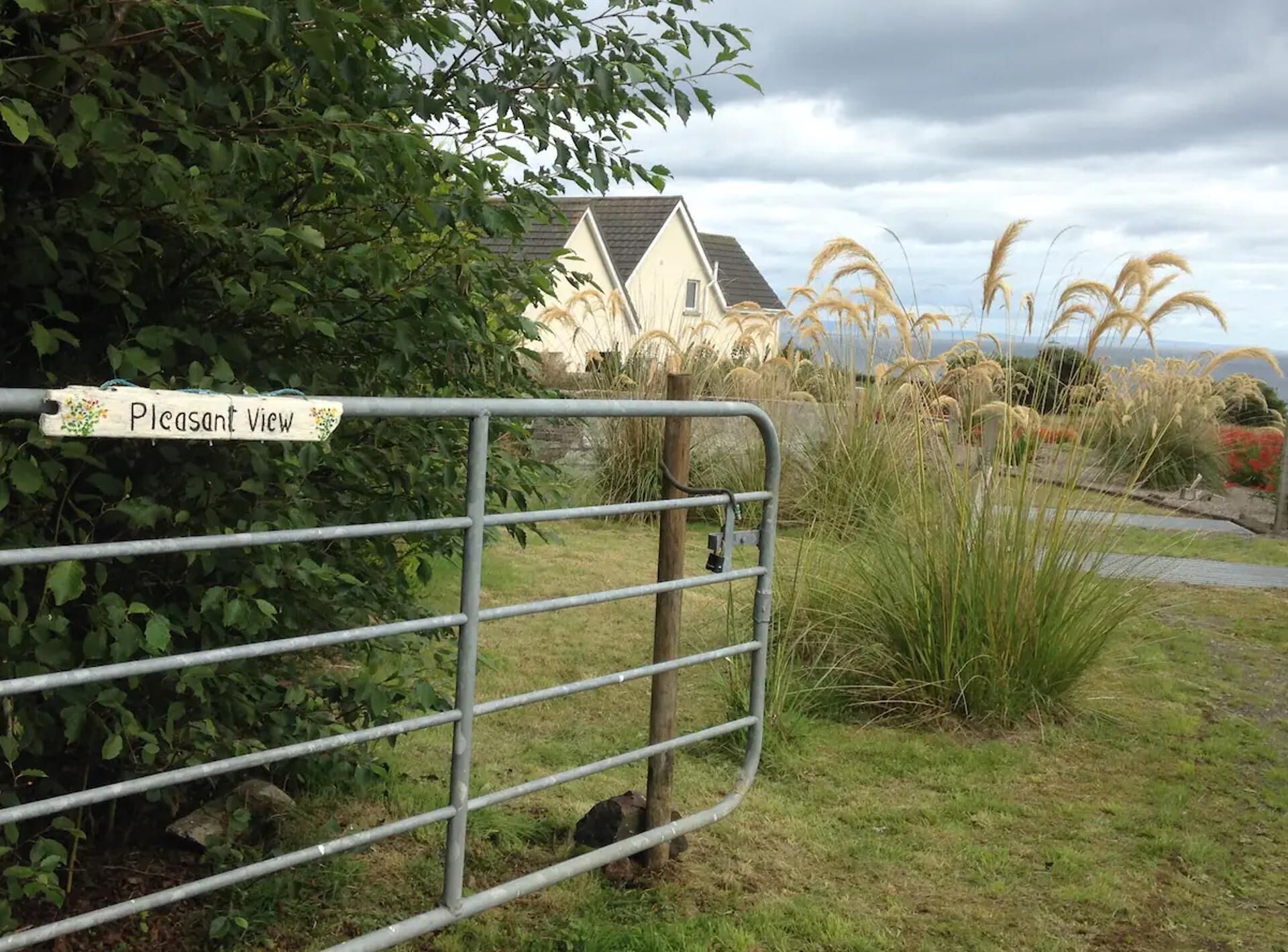A gated area with a sign reading "Pleasant View" and a house in the background.