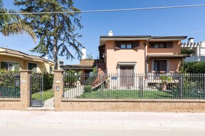 A two-story house with a paved driveway and a metal fence.