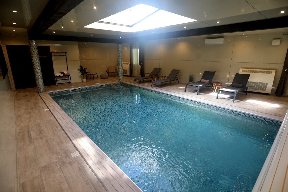 An indoor swimming pool with lounge chairs and a skylight.