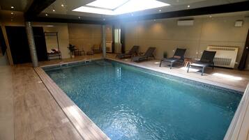 An indoor swimming pool with lounge chairs and a skylight.