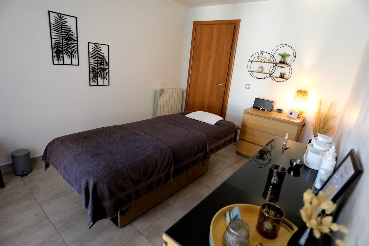 A bedroom with a bed, bedside table, lamp, and wall art.
