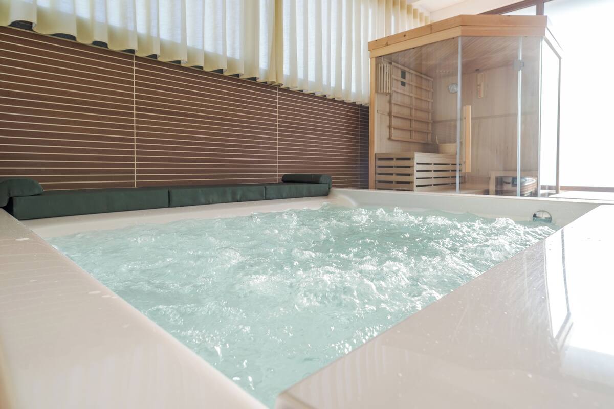 Egy modern wellnesszóna, amely jakuzzival, fa lamellákkal  és üvegfalakkal rendelkezik.