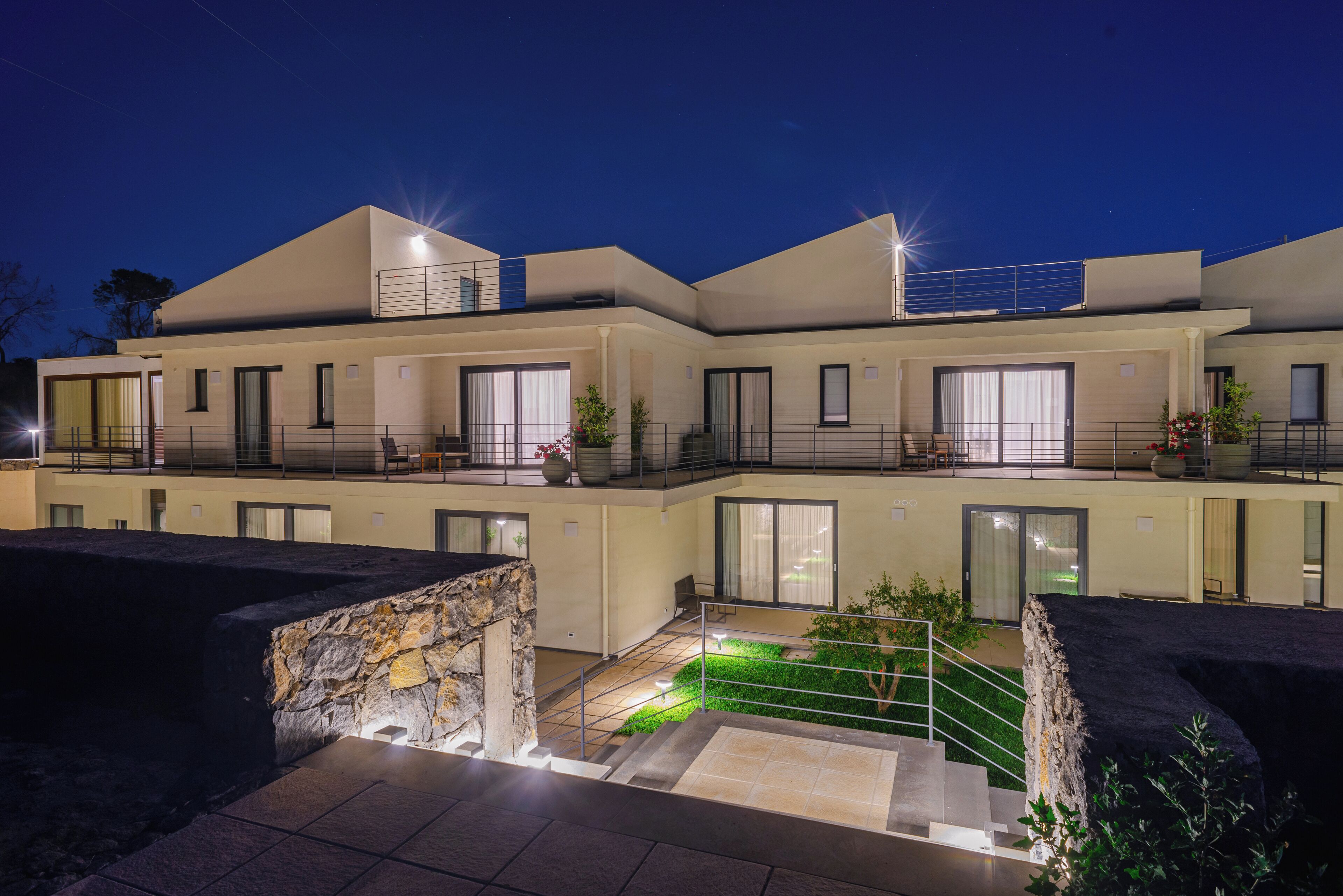 A modern multi-story residential building with balconies, large windows, and a landscaped courtyard.