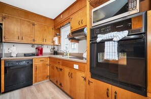A kitchen with wooden cabinets, a dishwasher, a microwave, and an oven.
