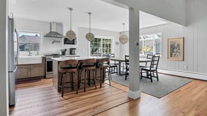 A modern kitchen with a central island, bar stools, and pendant lighting.