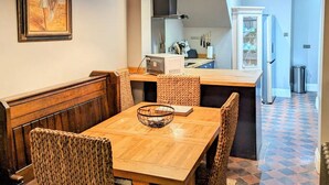 A dining area with a wooden table and woven chairs, a kitchen with modern appliances, and a patterned floor. - Beautiful apartment in Central London, Paddington (London)