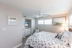 A bedroom with a bed, a ceiling fan, a window, and a door.
