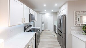 A modern kitchen with white cabinetry, stainless steel appliances, and a central island. - Villa 20 - Premium Plus (Siesta Key)