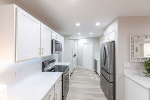 A modern kitchen with white cabinetry, stainless steel appliances, and a central island.