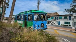A blue and green tram on a road with a building in the background. - Villa 20 - Premium Plus (Siesta Key)