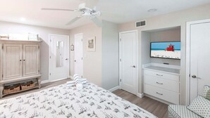 A bedroom with a bed, wardrobe, television, and a view of the beach. - Villa 20 - Premium Plus (Siesta Key)
