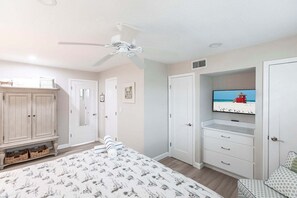 A bedroom with a bed, wardrobe, television, and a view of the beach.