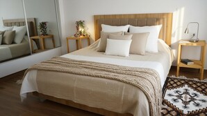A neatly made bed with a headboard, a bedside table with a lamp, a mirror, and a small plant. - Chic & cozy apartment with balcony, 2 bathrooms – Carthage, near the airport (Al Karm)