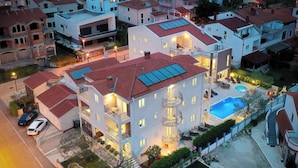 A multi-story hotel with a swimming pool, balconies, and a well-lit entrance. - Holiday apartment with air conditioning and outdoor pool (Fažana)