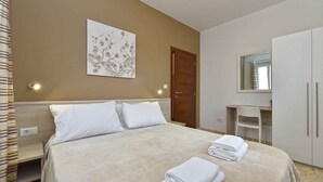 A hotel room with a bed, a bedside table, a mirror, a wardrobe, and a wall with a floral artwork.
