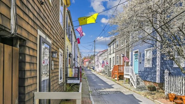 A narrow street lined with wooden houses, some with visible front porches and steps leading to the entrance. - Downtown Pinkney House w/Parking (Annapolis)