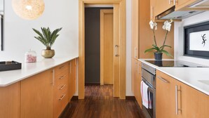 Una cocina moderna con armarios de madera, encimera blanca, lámpara colgante y una planta en maceta.