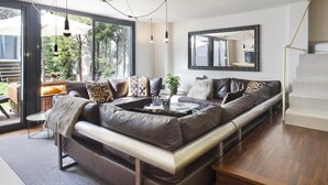 A modern living room with a leather sofa, a coffee table, and a large mirror.