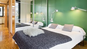 Moderni hotellihuone, jossa on suuri sänky, kaksi yöpöytävalaisinta ja yksi seinä, joka on maalattu vihreällä korostusvärillä.