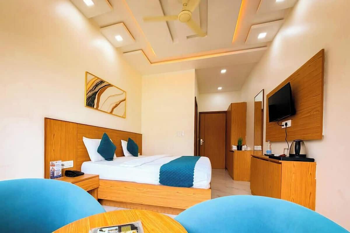 Ein Hotelzimmer mit Bett, Schreibtisch, Fernseher und Deckenventilator.