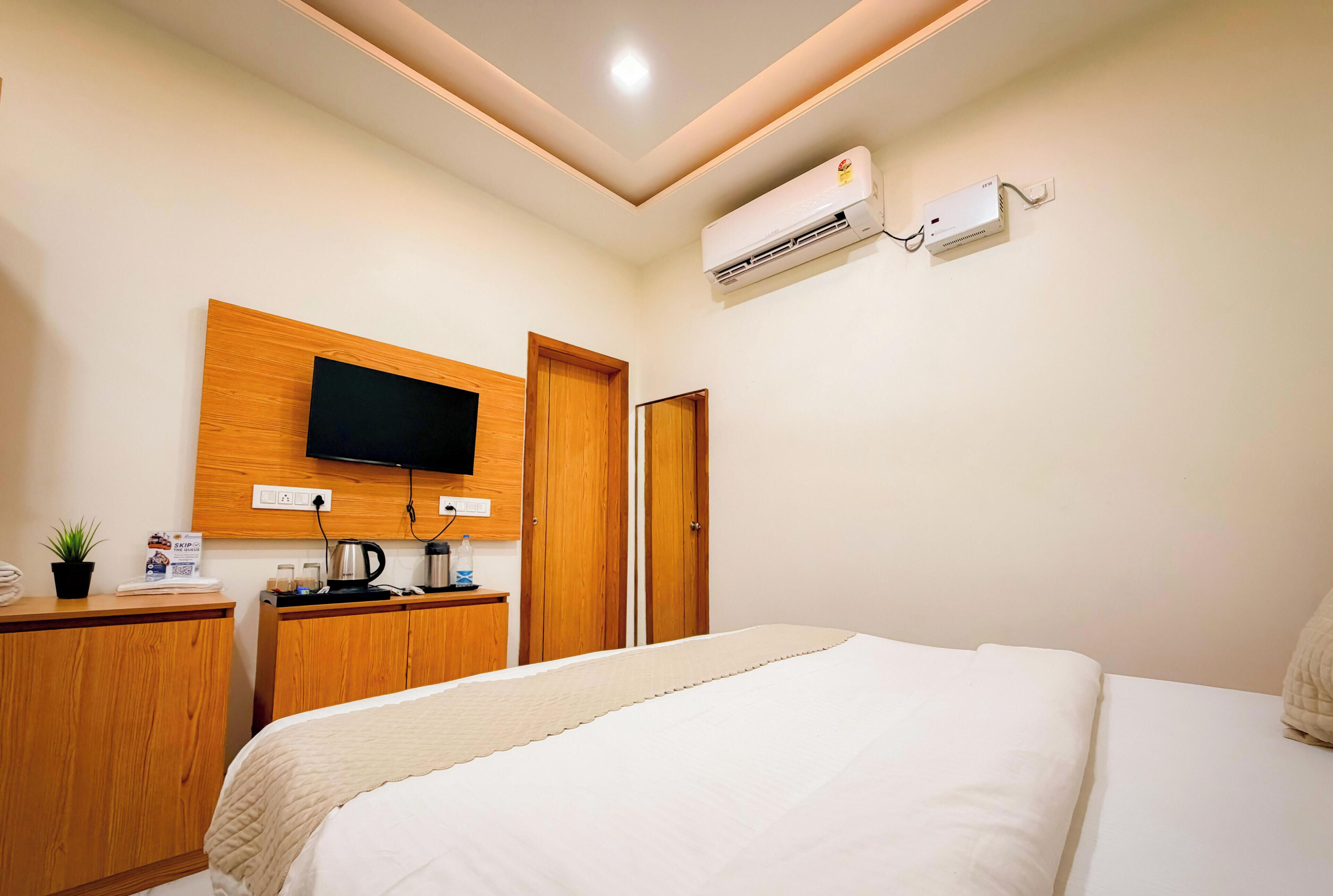 Ein Hotelzimmer mit Bett, Wandfernseher, Schreibtisch mit Kaffeemaschine und Klimaanlage.