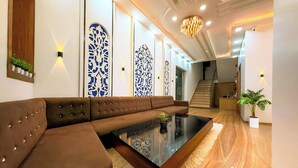 Una sala de estar moderna con un sofá seccional marrón, una mesa de centro de vidrio y paneles decorativos en la pared.