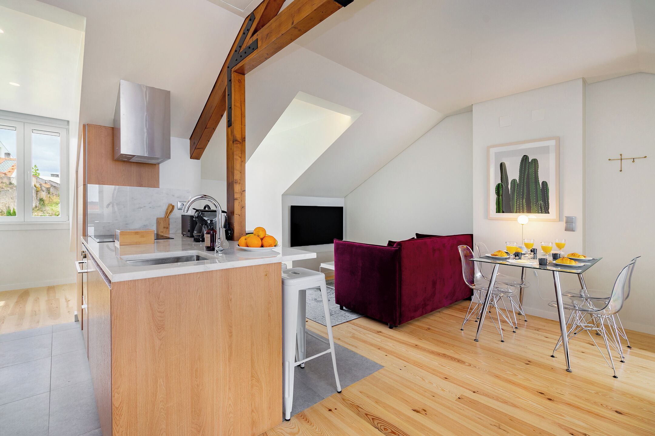 A modern kitchen with a central island, a dining area with a table and chairs, and a living space with a sofa.