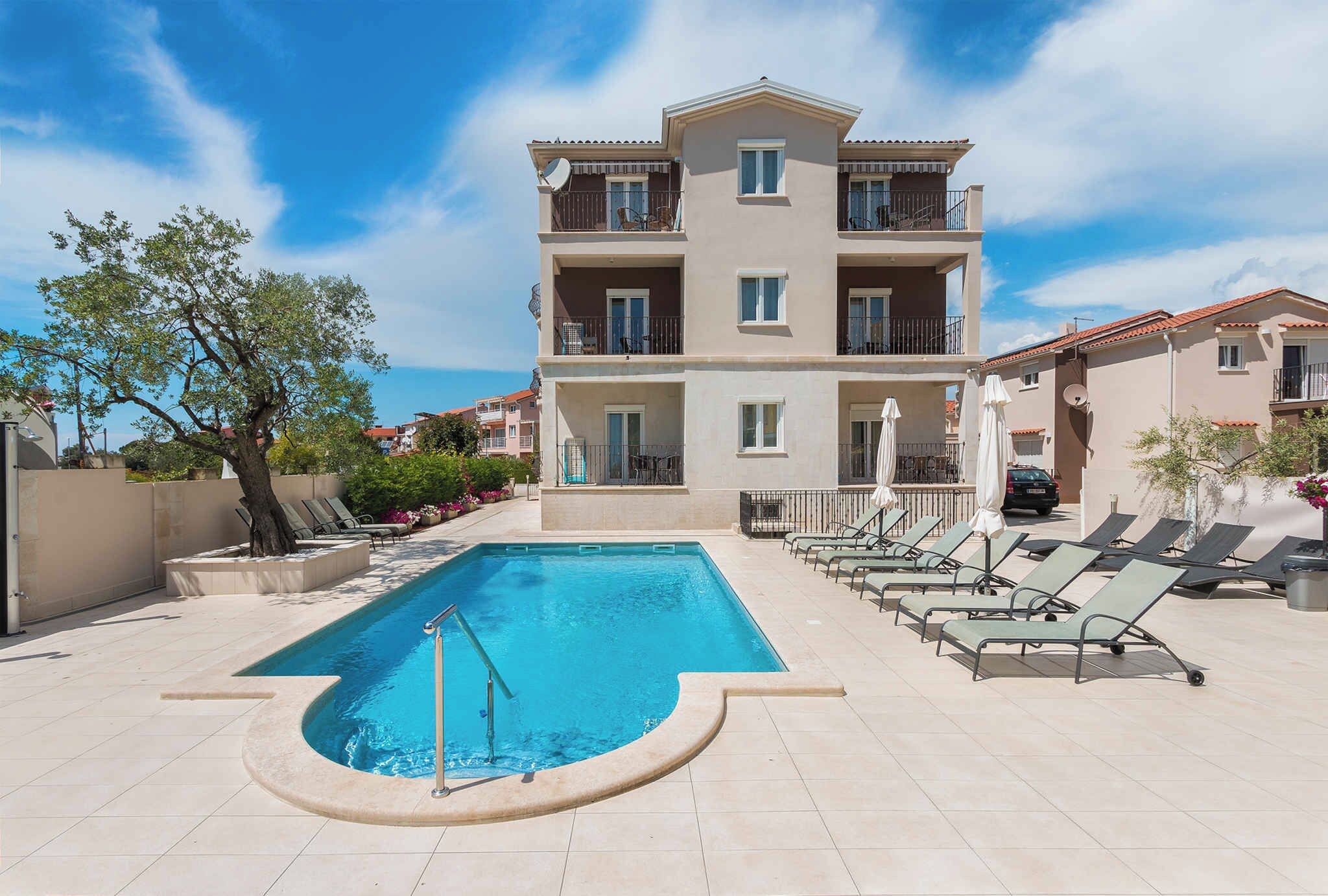 Une piscine avec des chaises longues et un bâtiment doté de balcons.