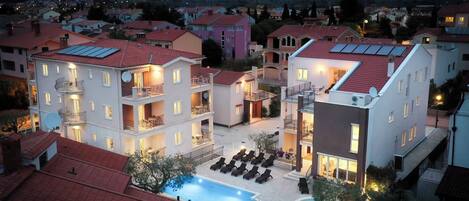 A multi-story hotel with a swimming pool, balconies, and a courtyard.