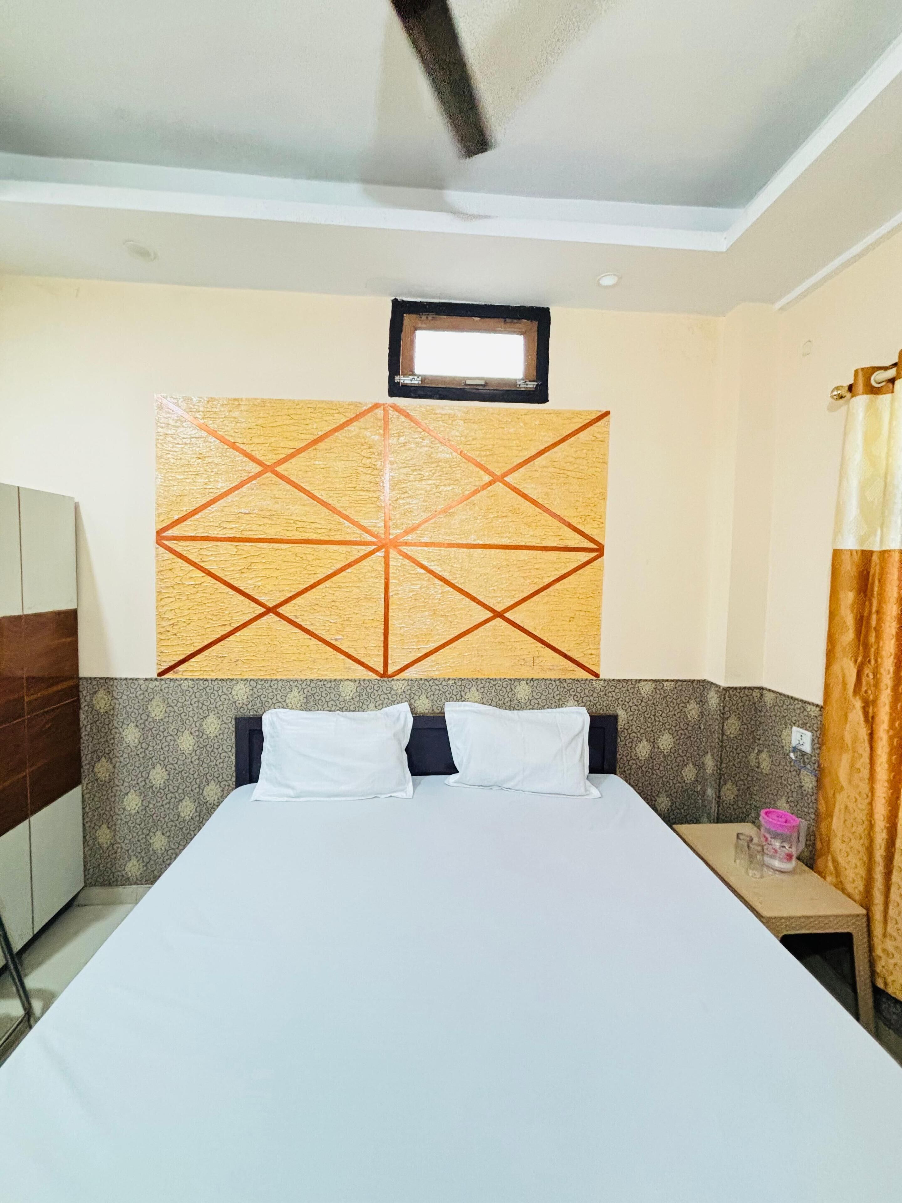 A hotel room with a bed, a nightstand, a window, and a wall-mounted artwork.