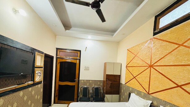 A hotel room with a bed, a television, a wardrobe, and a ceiling fan. - Dev Aagmann Inn  (Faizabad)