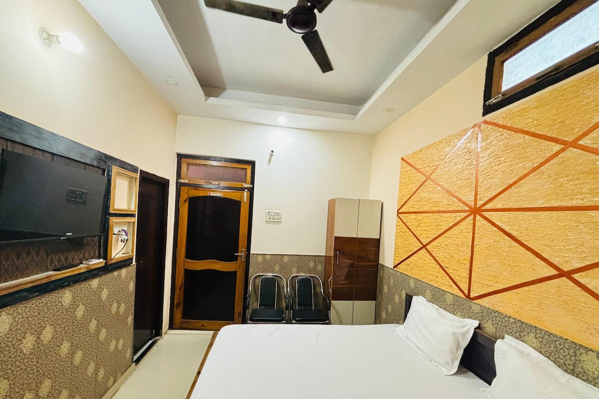A hotel room with a bed, a television, a wardrobe, and a ceiling fan.