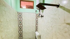 A small bathroom with a toilet, a shower, and a window. - Dev Aagmann Inn  (Faizabad)