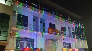 A building with multiple floors, decorated with colorful string lights. There are signs for 'Dev Mart' and 'Catch Khana'. - Dev Aagmann Inn  (Faizabad)