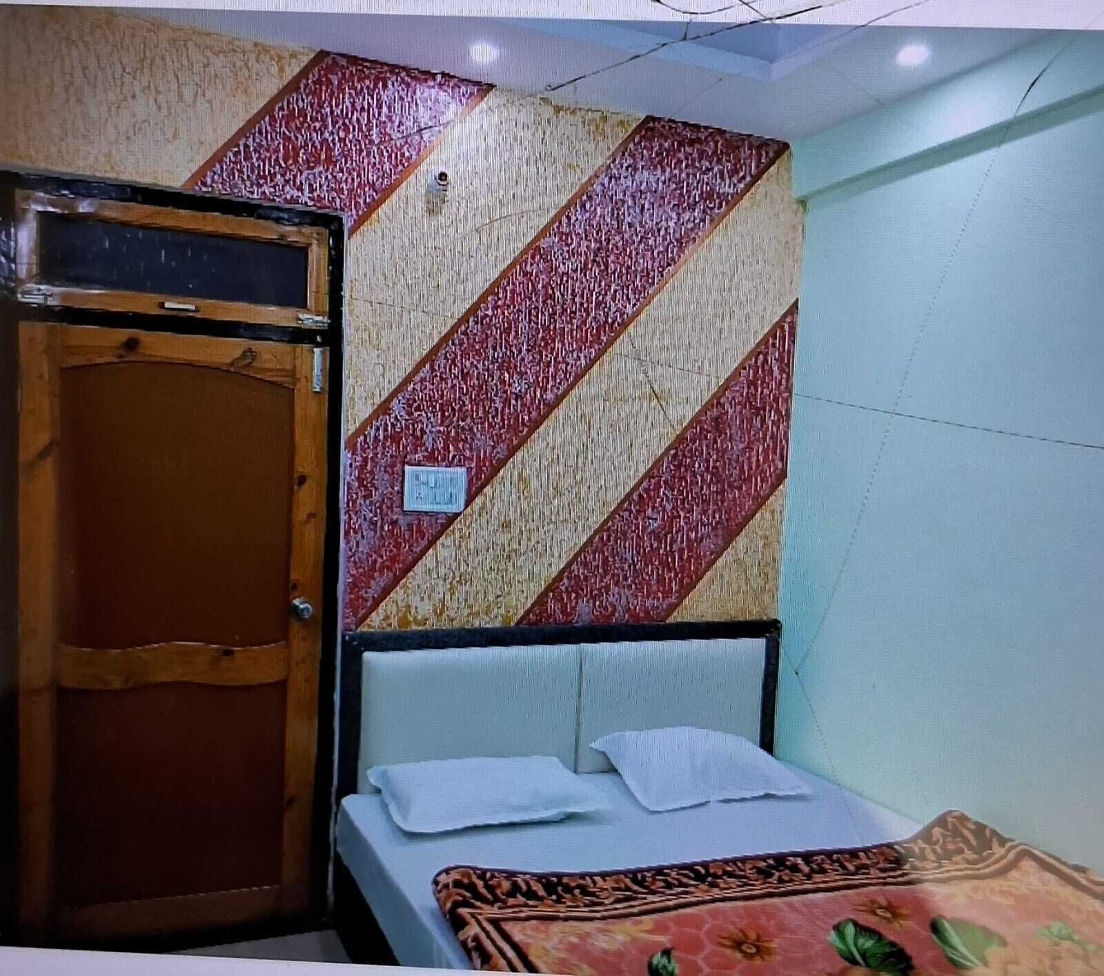 Una habitación con una cama, una puerta de madera y un papel tapiz estampado.