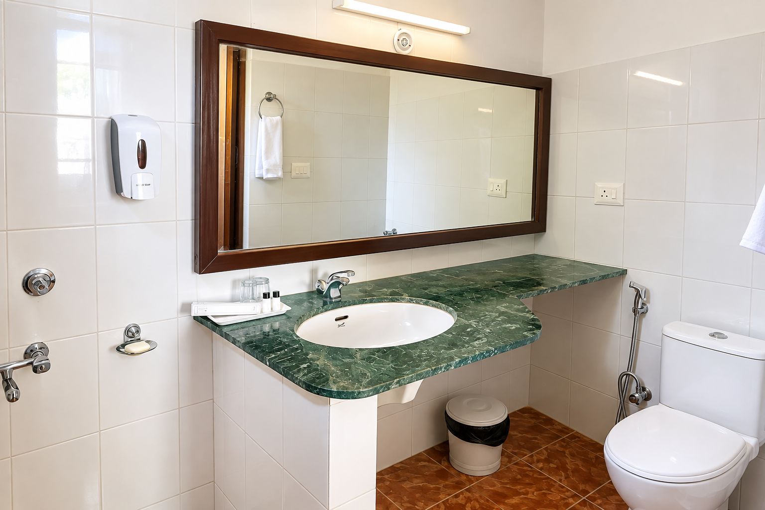 Un baño con lavamanos de mármol, espejo, toallero y retrete.